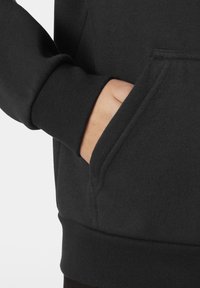 Černá mikina se klokankou, žebrovanými manžetami a lemem. Tkanina vypadá měkce, má hladkou strukturu a minimální designové detaily.