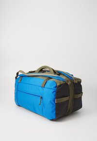Sac de sport bleu et noir avec des anses vert olive, de forme rectangulaire, poignée supérieure, poche zippée à l'avant et texture de matériau rembourrée.