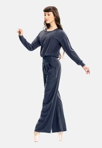 Dark blue long-sleeve top and wide-leg pants, both in a soft, smooth fabric. Features a fitted waist and ballet slippers.