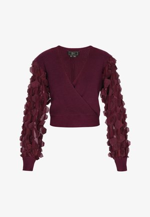 Viininpunainen villapaita, jossa on v-pääntie, teksturoitu neulevartalo ja läpikuultavat pöyhistetyt hihat, joissa on kerroksittain geometrisia koristeita.