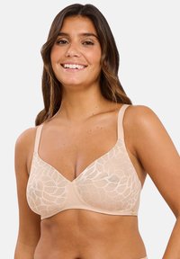 Beige kanten beha met bladrandpatroon, zachte stof, gevormde cups en verstelbare bandjes. Voorzien van een haak- en oogsluiting aan de achterkant.