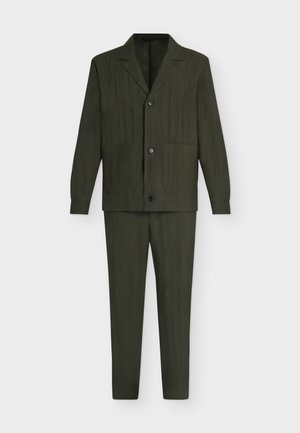 Ensemble costume deux pièces vert foncé avec une veste à col cranté comportant trois boutons et deux poches plaquées devant, associée à un pantalon fuselé assorti.