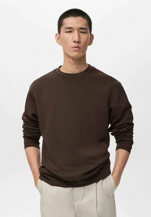 Sudadera marrón con cuello redondo, de manga larga y puños acanalados, combinada con pantalones gris claro, de textura suave.