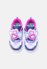 Παιδικά αθλητικά παπούτσια σε ροζ, μωβ και μπλε χρώμα με διακοσμήσεις σε σχήμα καρδιάς και φωτ εινή ροζ εσωτερική επένδυση, τοποθετημένα δίπλα-δίπλα πάνω σε λευκό φόντο.