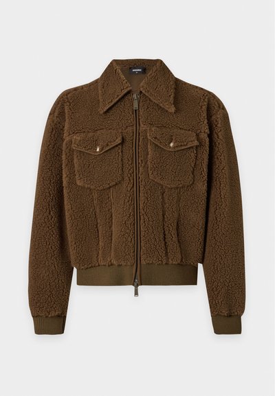 Veste sherpa marron zippée avec deux poches avant à rabat, col large et poignets et bas côtelés sur un fond neutre.