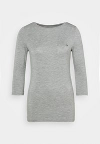 Vaaleanharmaa pitkähihainen naisten paita, jossa on venepääntie ja pieni brodattu logo vasemmassa ylärinnassa.