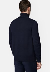 Granatowy sweter dzianinowy z wysokim kołnierzem oraz ściągaczami przy mankietach i u dołu. Teksturowana tkanina o dopasowanym kroju, widok z tyłu.