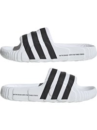 Črno-bela drsna obuvala z teksturiranim dizajnom, ki imajo tri izrazite črne črte čez vrh. Narejena iz sintetičnega materiala.