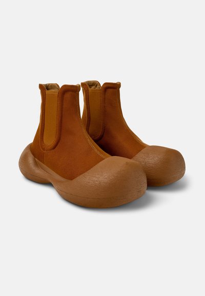 Bottines en tissu marron avec une semelle en caoutchouc, un bout arrondi, des côtés élastiques et une surface texturée. Conçues pour le confort et la flexibilité.
