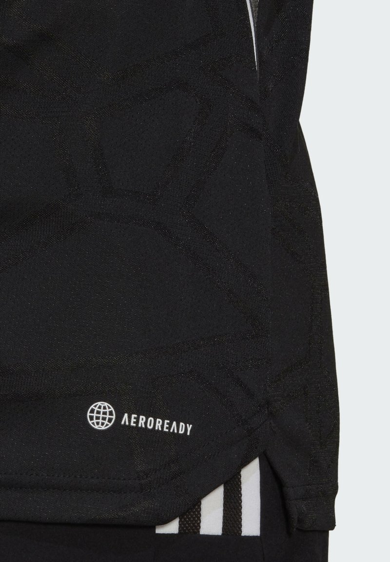 Camiseta atlética negra con un patrón geométrico texturizado, hecha de material transpirable, con un logo blanco "AEROREADY" cerca del dobladillo.