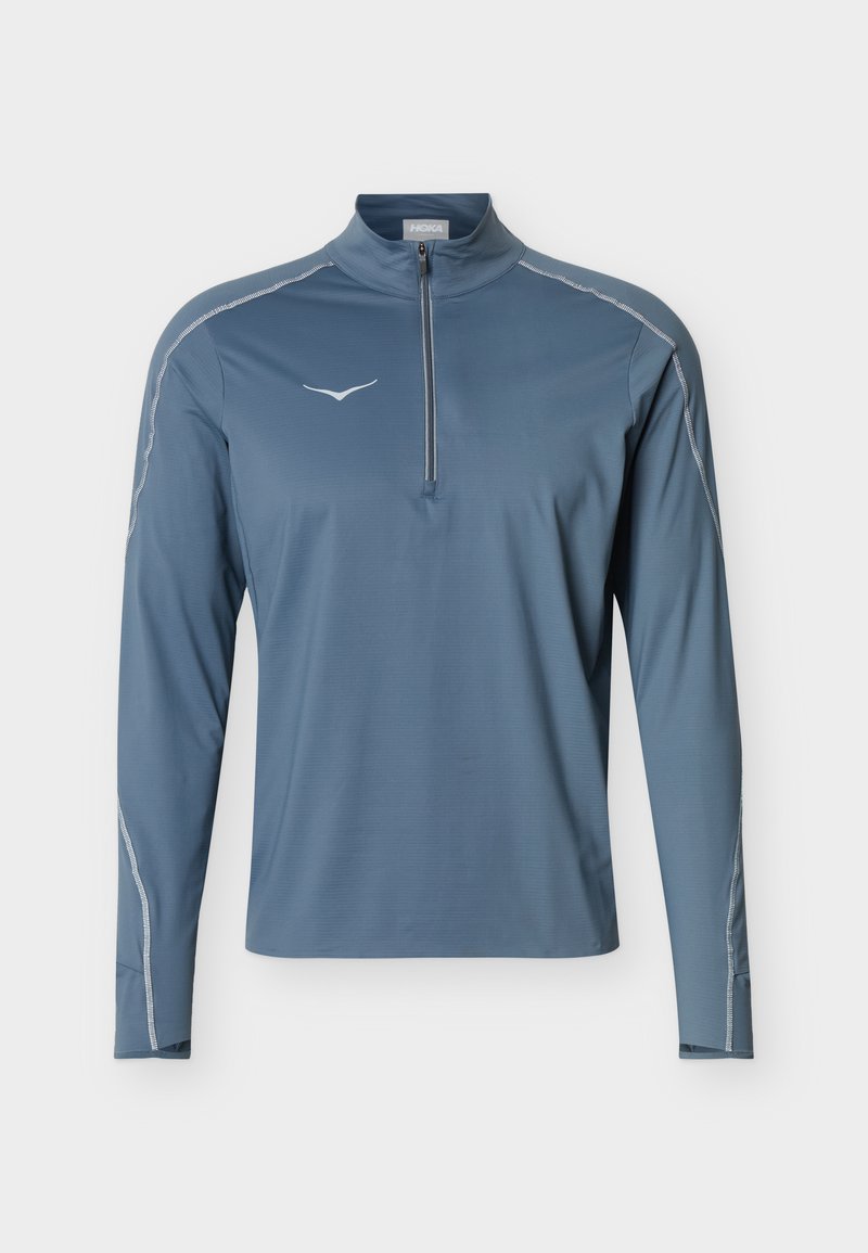 Pulóver deportivo azul de manga larga para hombre con cremallera de cuarto de cierre, logo blanco en el pecho y costuras reflectantes a lo largo de las mangas y los hombros.