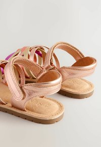 Rosen goldene Sandalen mit Lederträgern, strukturiertem beigem Fußbett und einer Gummisohle. Die Riemen sind in schichtweisen Pastellfarben in Rosa und Gold gehalten.