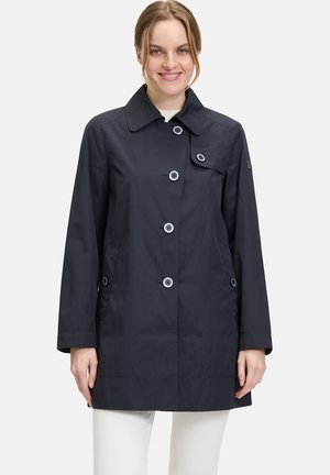 Manteau imperméable bleu marine avec un col pointu, des boutons à l'avant et des poches latérales. Présente des accents de boutons bleus contrastants.