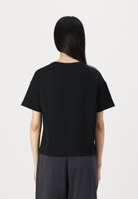 Černé krátké tričko s krátkými rukávy, kulatým výstřihem a hladkou texturou; disponuje jednoduchým designem bez ozdob.