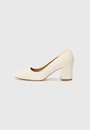 Pompe à talons hauts blanches avec un bout pointu, en matériau synthétique lisse, et un talon large. Design minimaliste avec une silhouette épurée.