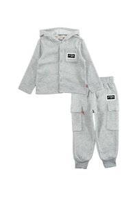 Sweat à capuche gris avec boutons et poche, associé à un pantalon de survêtement gris avec poches cargo et ceintures élastiques. Tissu doux, design décontracté.