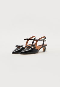 Sorte patentlæder slingback-sko med spids tå, lille hæl og dekorativ sløjfeaccent på den forreste rem.