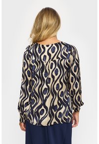 Tryckt blus med en beige bas och marinblå abstrakta v�ågiga samt ovala mönster, lång ärm och smockade ärmslut; lättviktsmaterial.
