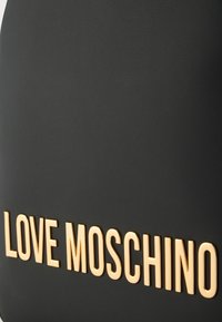 Μαύρη τσάντα από συνθετικό δέρμα με έντονη χρυσή επιγραφή "LOVE MOSCHINO". Λείο υλικό με μινιμαλιστικό σχεδιασμό.