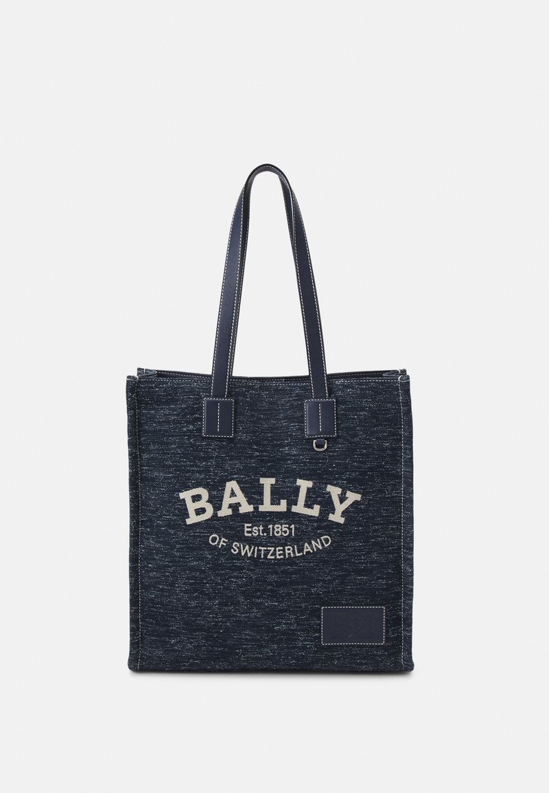 Sac fourre-tout en tissu bleu foncé avec deux longues poignées et texte blanc "BALLY Est. 1851 OF SWITZERLAND" sur le devant.