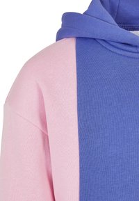 Felpa con cappuccio caratterizzata da un design a contrasto, con il lato sinistro di un rosa tenue e il lato destro di un blu vivace. Tessuto morbido, materiale misto cotone.