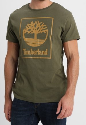Olive green short-sleeve t-shirt made of cotton, featuring a gold Timberland logo with a tree design in a square outline.