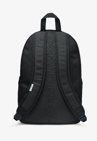 Černý plátěný batoh s polstrovanými popruhy a horním madlem, s vyraženým nápisem „CONVERSE“ na přední straně. Obsahuje boční kapsy pro uložení.
