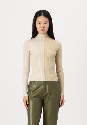 Ribbete turtleneck-genser i to nyanser av beige, tettsittende design. Kombinert med høyt liv olivengrønne skinnbukser, glatt tekstur.
