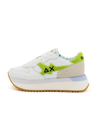 Sneaker bianca con accenti verdi e grigi, caratterizzata da una parte superiore testurizzata, chiusura con lacci e una suola spessa con un design seghettato.