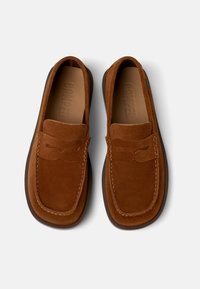 Brown suede loafers with a moccasin-style design, featuring tonal stitching and a simple bow accent on the front. Flat rubber sole.