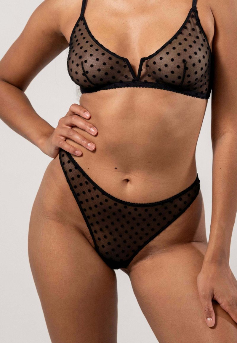 Ensemble bralette et string noir en dentelle transparente avec un motif à pois, doté d'un ourlet festonné et de bretelles réglables. Tissu doux et léger.