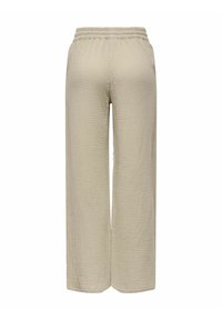 Beżowe spodnie o szerokich nogawkach z teksturowanej tkaniny, z elastycznym pasem i bez widocznych kieszeni. Prosty, prosty krój.