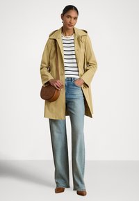 Khaki pršiplášť s kapucňou, pruhované bielo-námornícke tričko, svetlomodré rifle s rovnými nohavicami a hnedá kabelka. Hnedé topánky so špicatou špičkou.