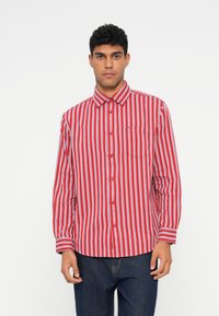 Rødrutete skjorte med knapper, brystlomme, krage og lange ermer, kombinert med mørkeblå jeans.