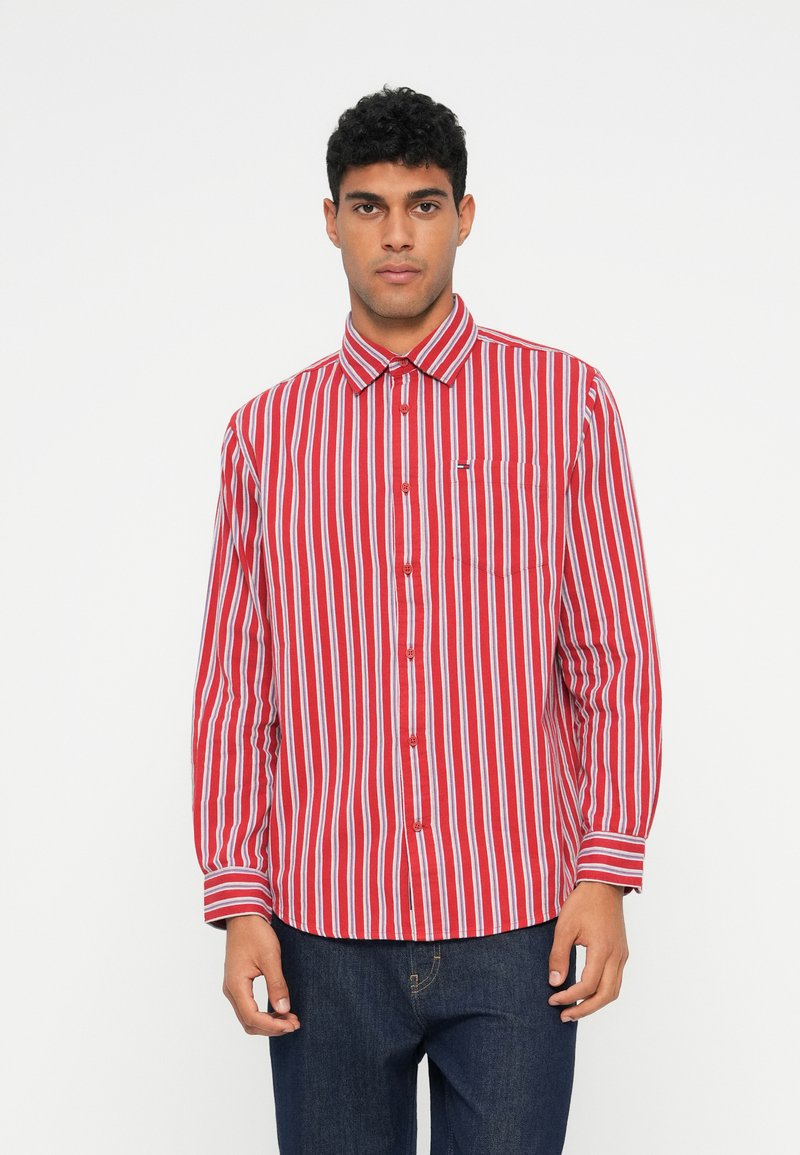 Rødrutete skjorte med knapper, brystlomme, krage og lange ermer, kombinert med mørkeblå jeans.