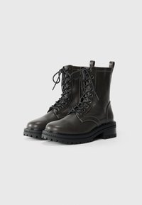 Bottines en cuir gris foncé avec lacets à l'avant, bout rond, semelle épaisse en caoutchouc, languette à l'arrière et détails de surpiqûres contrastées.
