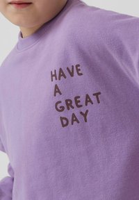 Felpa lavanda con scollo tondo. Scritta "HAVE A GREAT DAY" stampata in carattere marrone scuro sul davanti. Materiale in cotone morbido, vestibilità comoda.