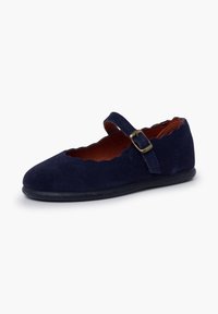 Chaussure Mary Jane en daim bleu marine avec bords festonnés, bride réglable à boucle et semelle plate noire sur fond blanc.
