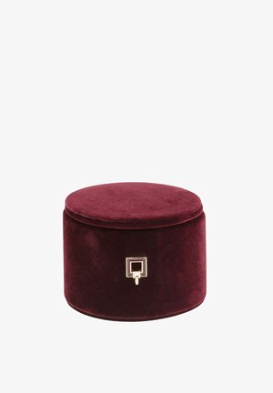 Caja de joyería redonda de terciopelo en color burdeos, con una textura suave y detalles en hardware dorado. Cuenta con una tapa segura y una forma compacta.