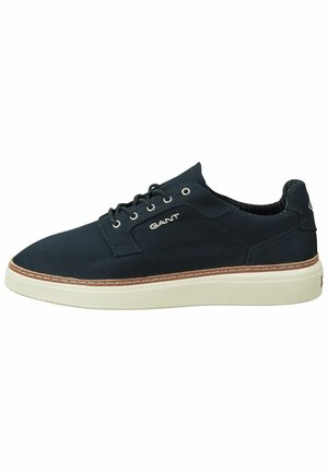 Baskets décontractées noires à lacets avec semelle blanche, bordure marron et logo GANT sur le côté.