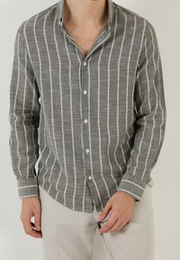 Grijs en wit gestreept overhemd met lange mouwen en een knoopsluiting kraag, gemaakt van een gestructureerde stof, met een lichte glans en knopen aan de voorkant.