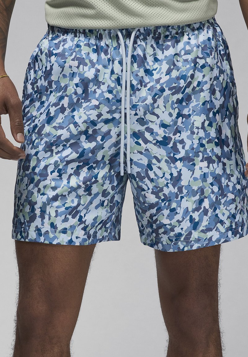 Shorts de bain courts avec un motif de camouflage abstrait bleu et vert. Fabriqués en tissu léger et brillant, dotés d'une taille élastique et d'un cordon de serrage.