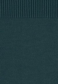 Σκούρο teal πλεκτό ύφασμα με ραβδωτή υφή στην κορυφή και ομαλή πλεκτή επιφάνεια από κάτω.