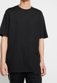 Svart kortärmad t-shirt i avslappnad passform, tillverkad av mjuk bomull, med rund halsringning och slät yta, utan mönster eller grafik.