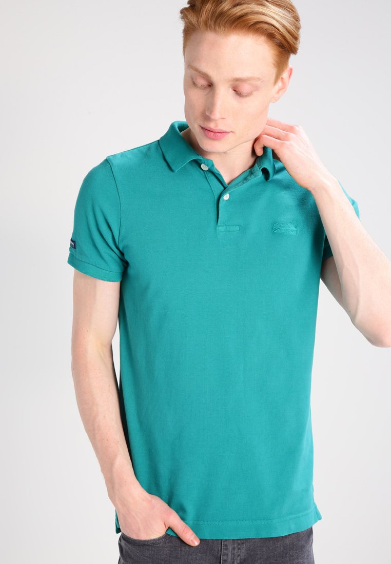 Polo shirt color teal realizzato in cotone, con colletto, due bottoni e un piccolo logo sul petto. Maniche corte e vestibilità dritta.