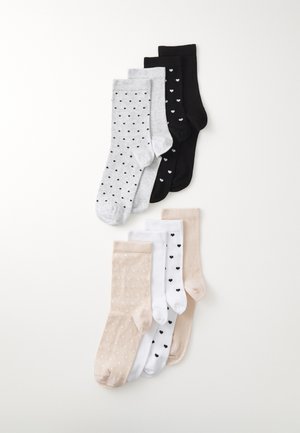 Vier paren sokken: grijs met zwarte stippen, zwart met kleine witte hartjes, beige met witte stippen en wit met zwarte stippen.