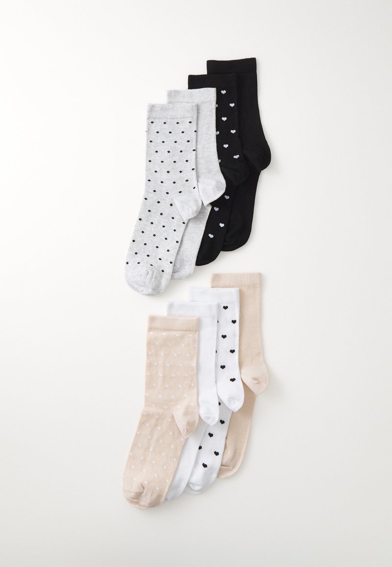 Vier Paar Socken: grau mit schwarzen Punkten, schwarz mit kleinen weißen Herzen, beige mit weißen Punkten und weiß mit schwarzen Punkten.