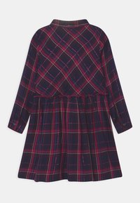 Kostkované šaty s dlouhými rukávy, námořnická základna, červené a růžové pruhy, knoflíkové manžety, stažený pas a splývavá sukně. Měkká textura látky.