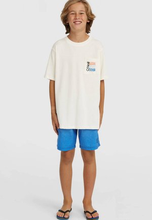 Valge puuvillane lühikeste varrukatega t-särk esitaskuga, millel on värvikas tekst. Ühildatud siniste lühikeste pükste ja mustade plätudega.