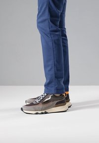 Baskets avec un mélange de gris, marron et accents orange ; matériau synthétique ; design bas ; semelle blanche épaisse ; motif en zigzag sur la semelle extérieure.